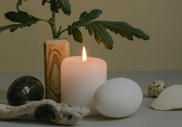 image of lit candle with rocks and a plant